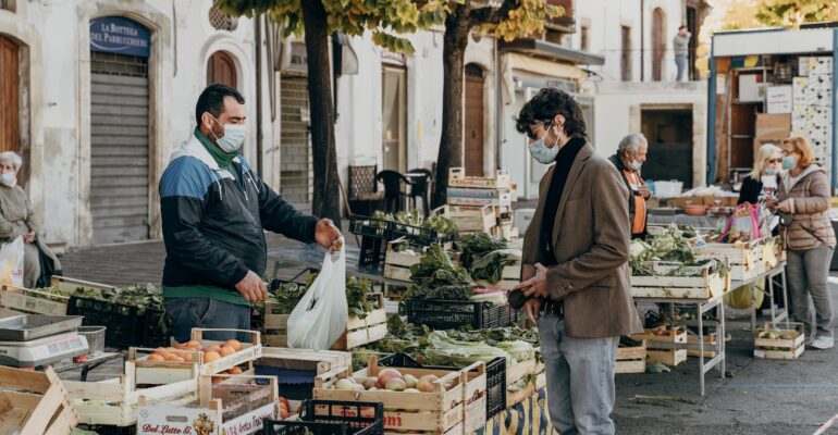 man in green jacket standing in front of food stall