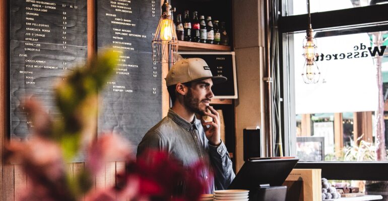 man wearing brown cap in across menu board
