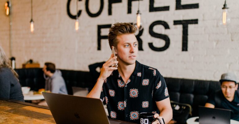 man holding phone white using MacBook